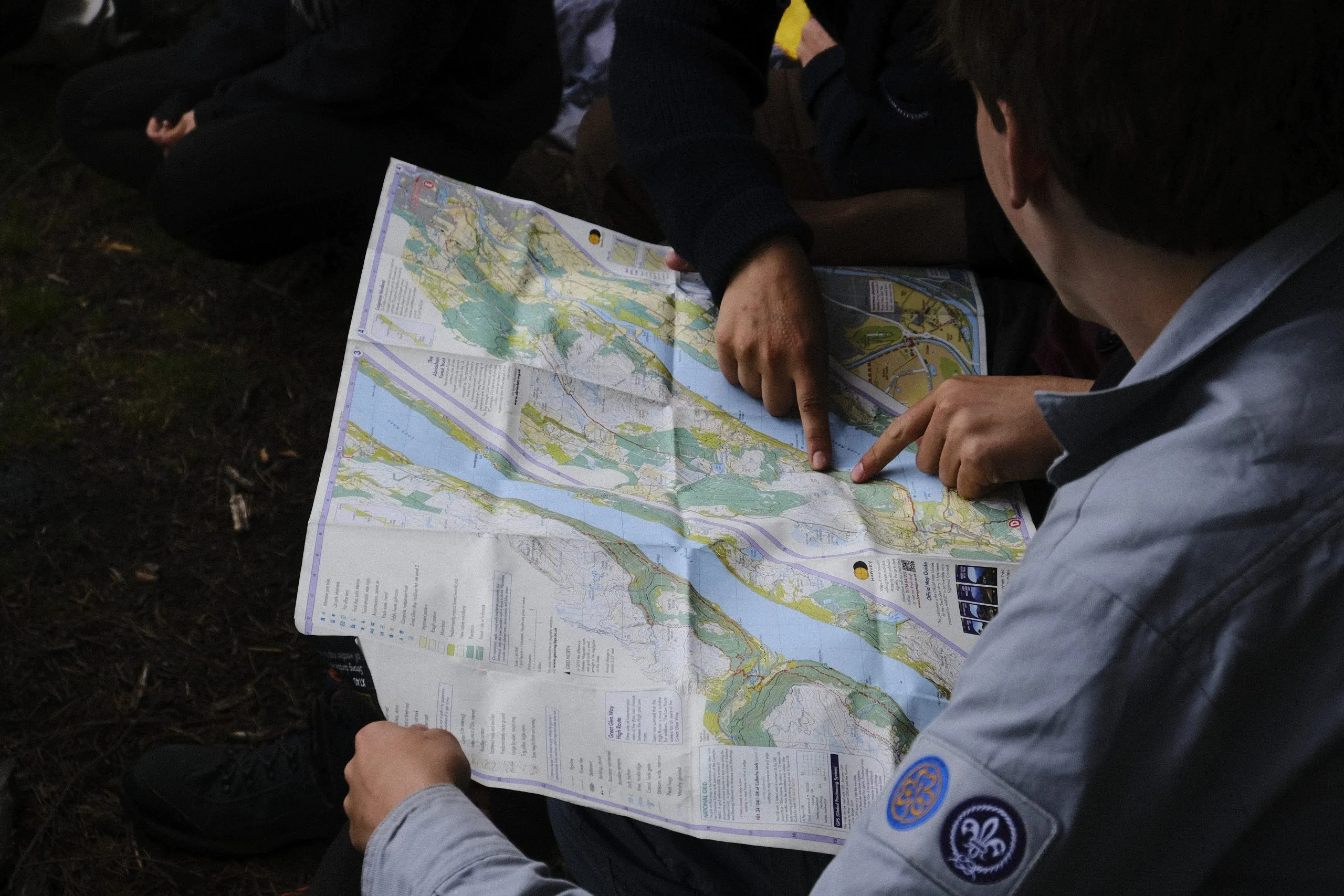 Pfadfinder in Kluft zeigen mit den Fingern auf eine ausgebreitete Wanderkarte